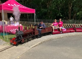 Two St Luke's volunteers riding a miniature train