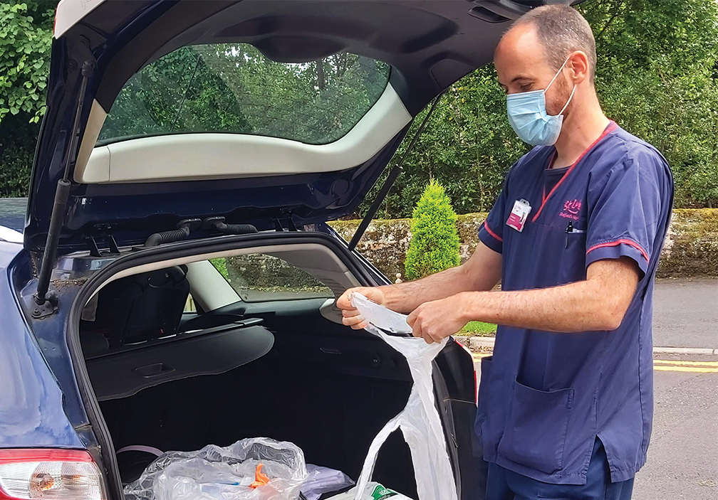 A photograph of Dave from our Community team. He is getting PPE out of his car boot on a patient visit.